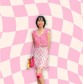 Katkat wearing an all-pink outfit: a floral dress, crochet vest, baag, and knee cover.